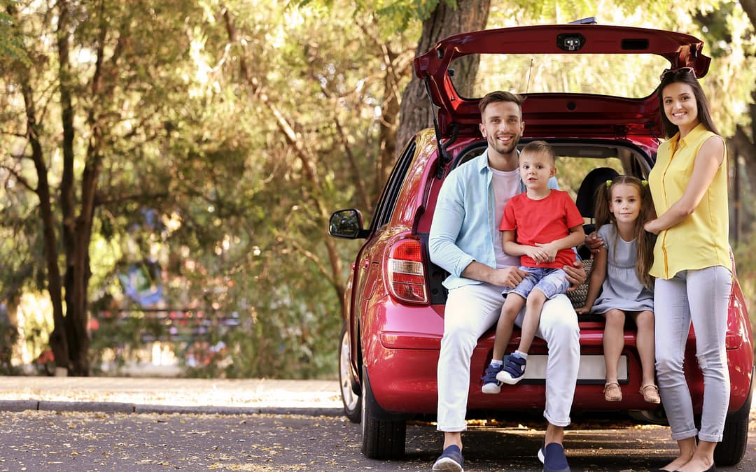 Family With Kids Sitting In Car Trunk