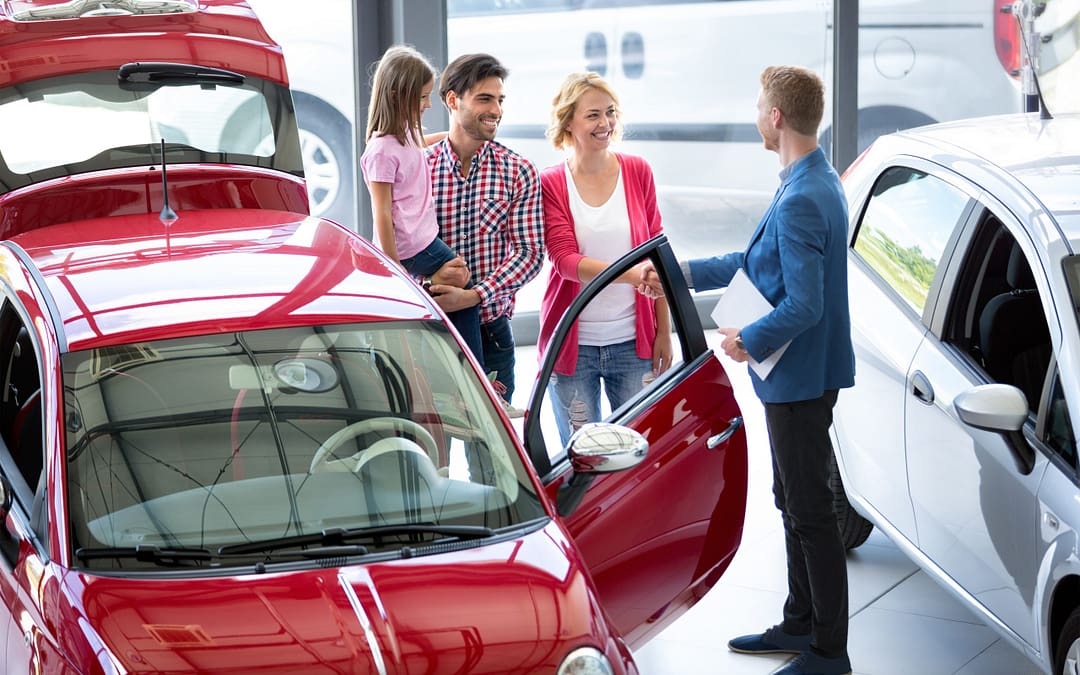 Car Agent Showing Vehicle To Young Family